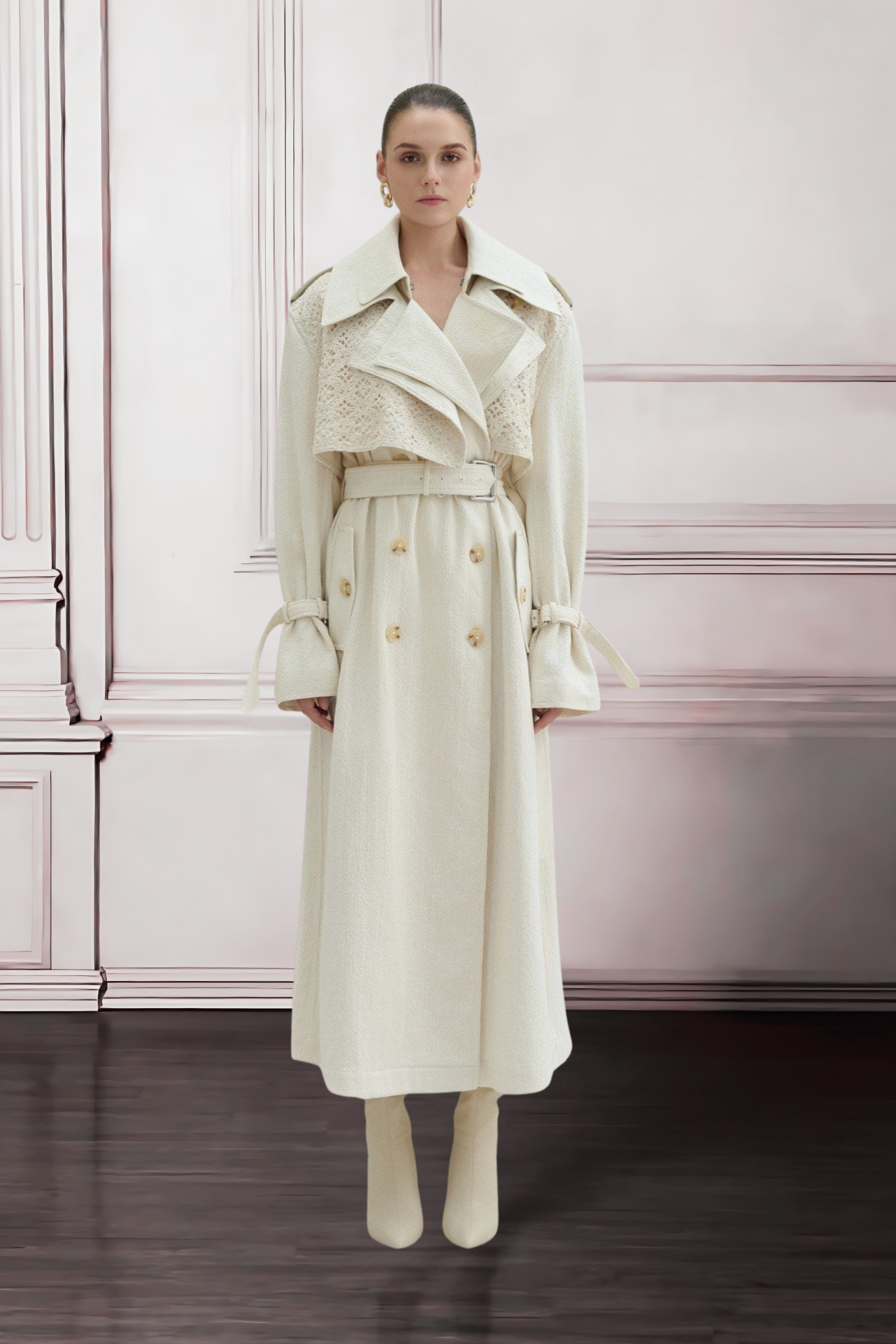 Woman wearing a cream-colored trench coat in an elegant room with pink walls.
