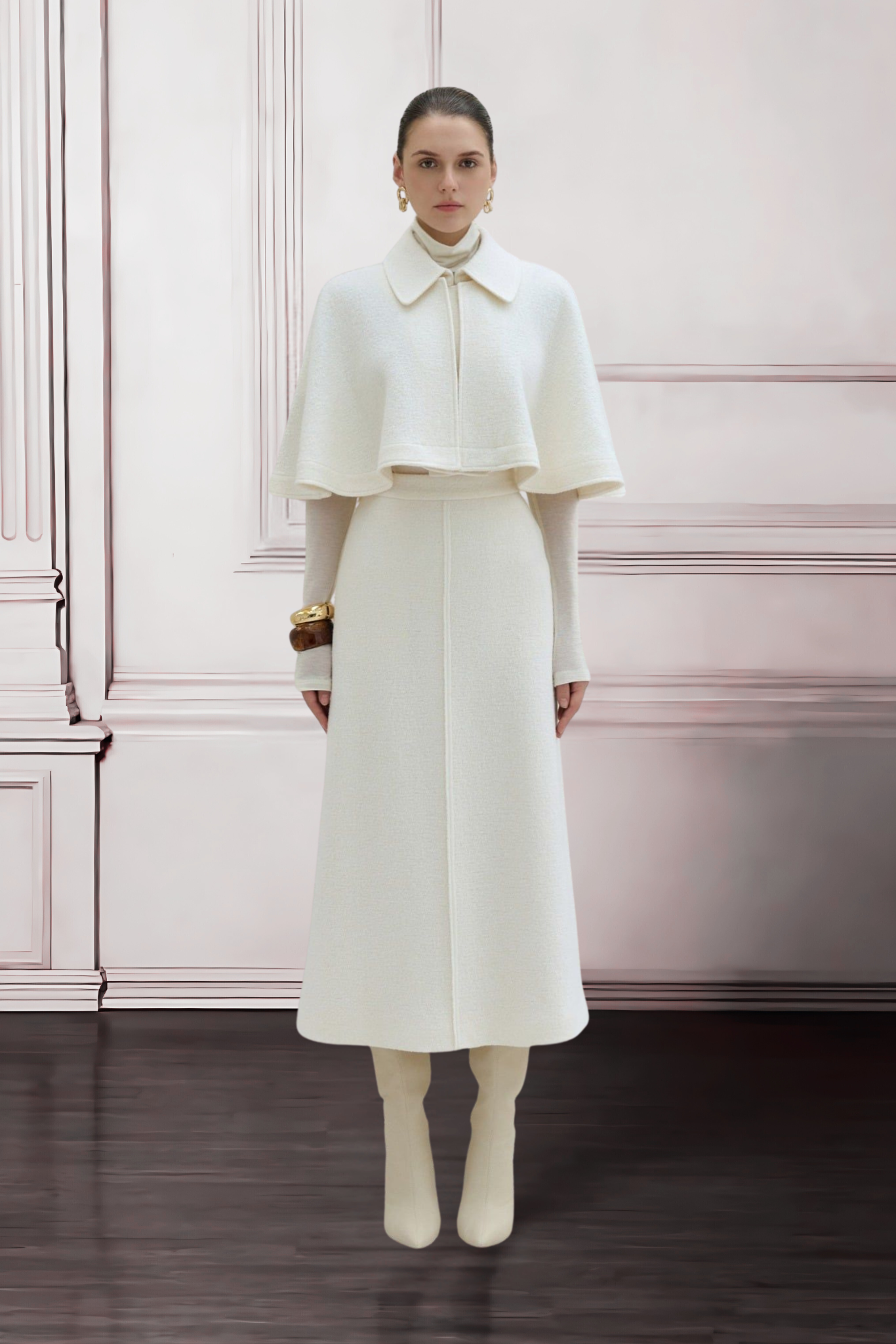 Woman wearing a white outfit with a cape against a pink wall.