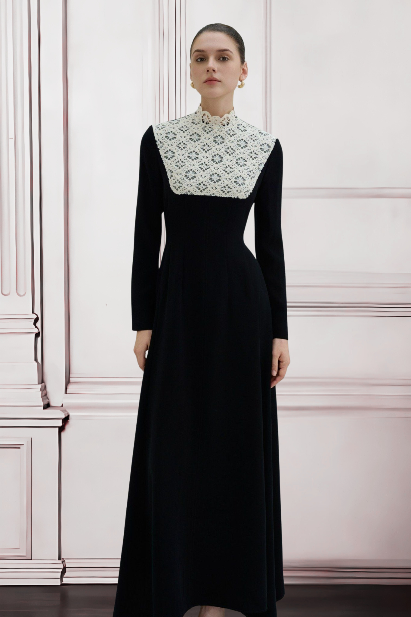 Woman wearing a black dress with a white embroidered collar against a white wall.